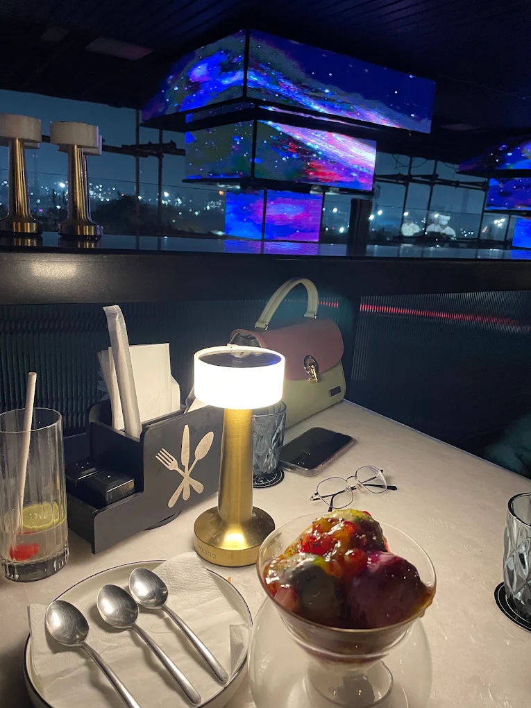 A lounge booth under galaxy light panels, a brass lamp on the table.