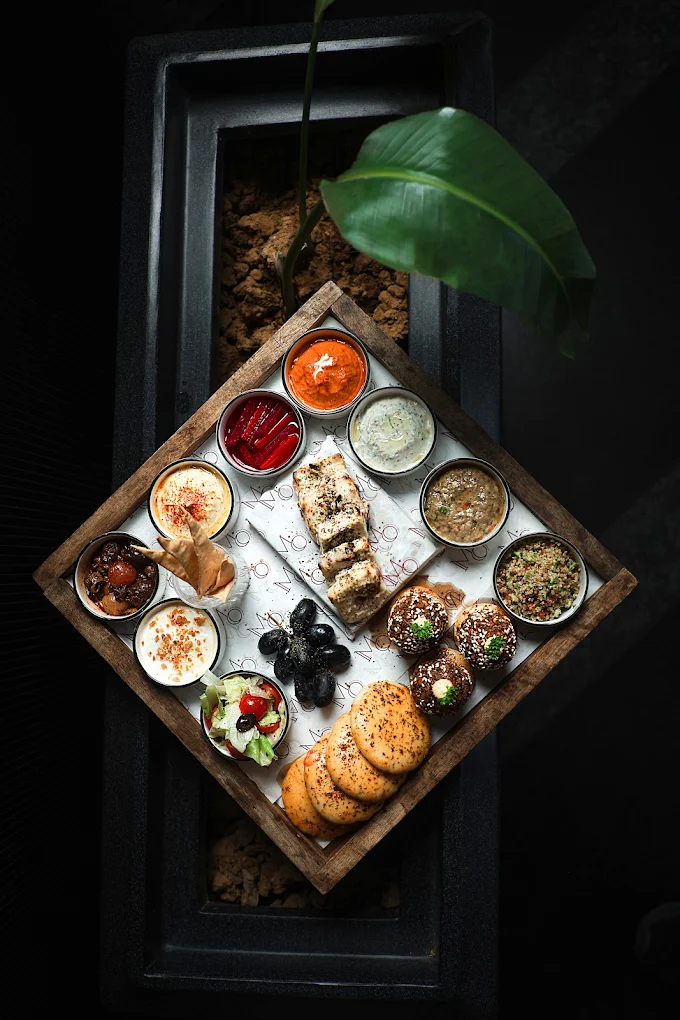 A mezze board shot from above — dips, breads, olives and salad on a diamond tray.