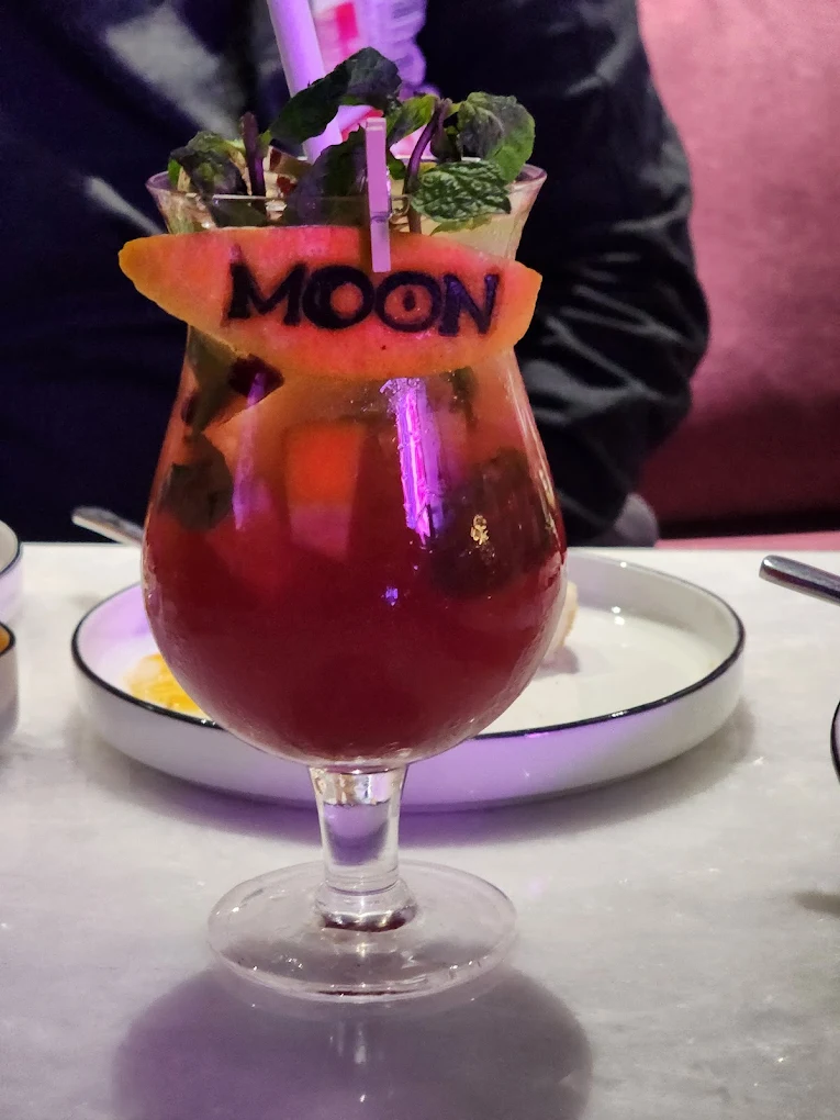 A house mocktail with a watermelon garnish stamped MOON.