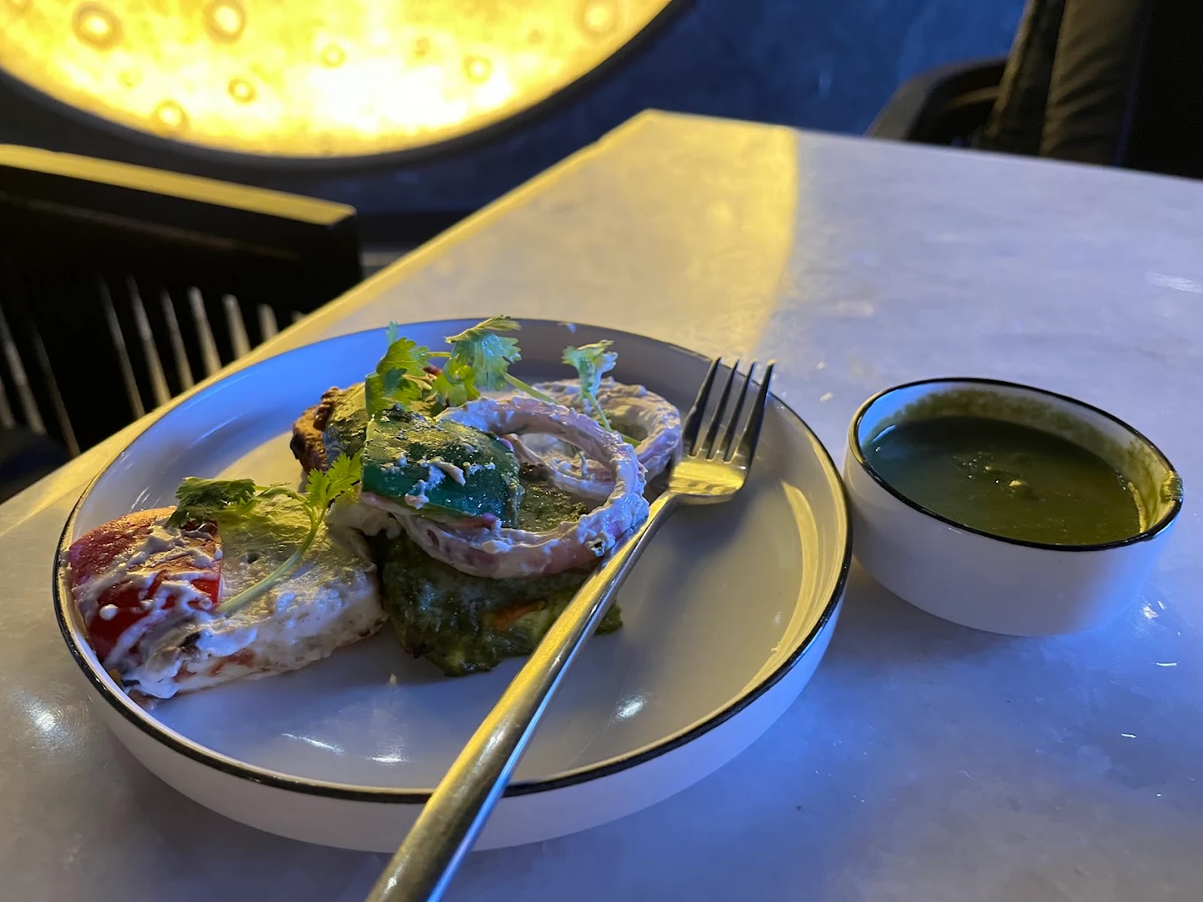 A paneer starter with green chutney, the amber moon wall glowing out of focus behind.