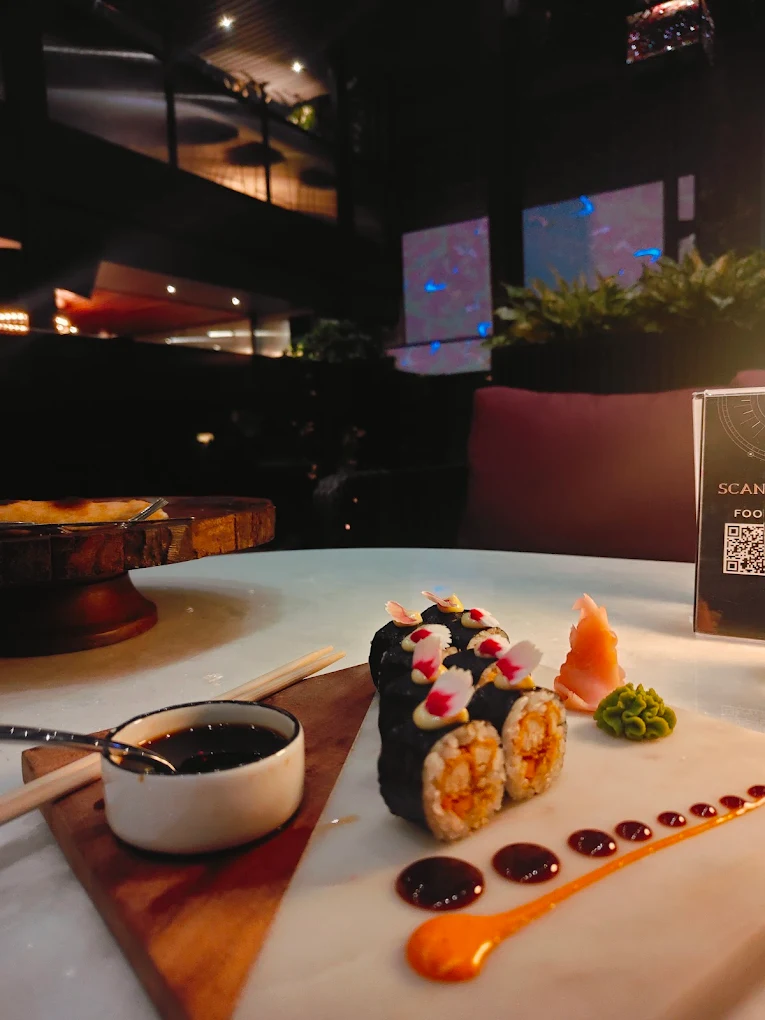 Sushi rolls on a marble slab with soy, wasabi and pickled ginger, the lounge behind.