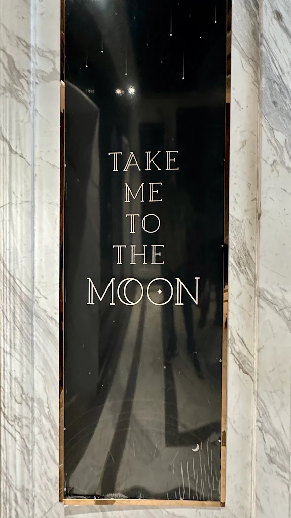 A marble entry panel reading “Take me to the Moon”.